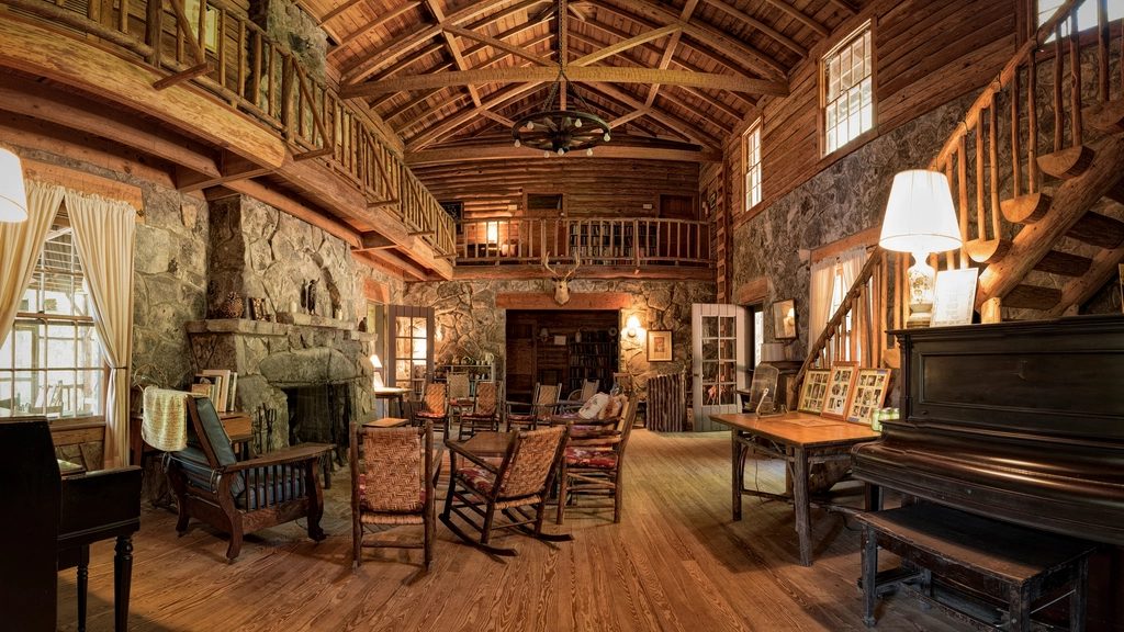 Sala de casa rústica com teto de madeira e lareira de pedra