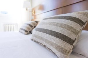 Travesseiros listrados sobre cama com lençol branco