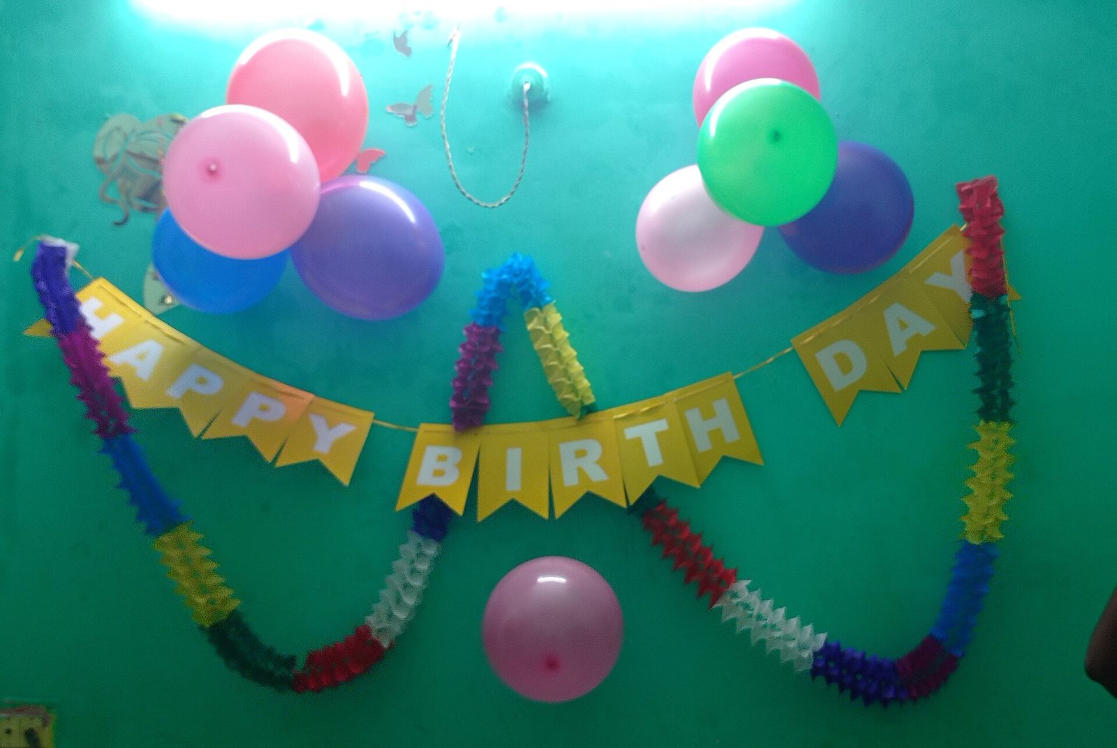 Parede decorada com bexigas coloridas e faixa de feliz aniversário