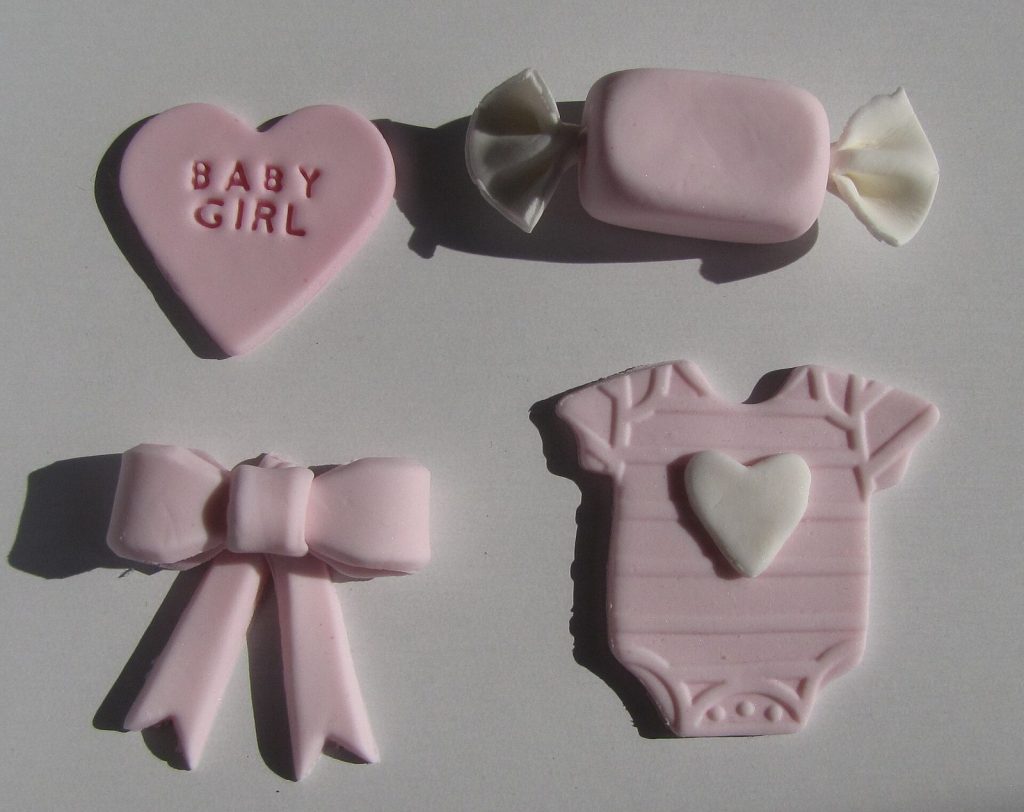 Biscoitos decorados em formato de body, laço e coração para chá de bebê