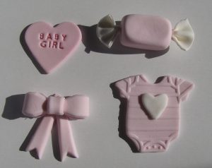 Biscoitos decorados em formato de body, laço e coração para chá de bebê