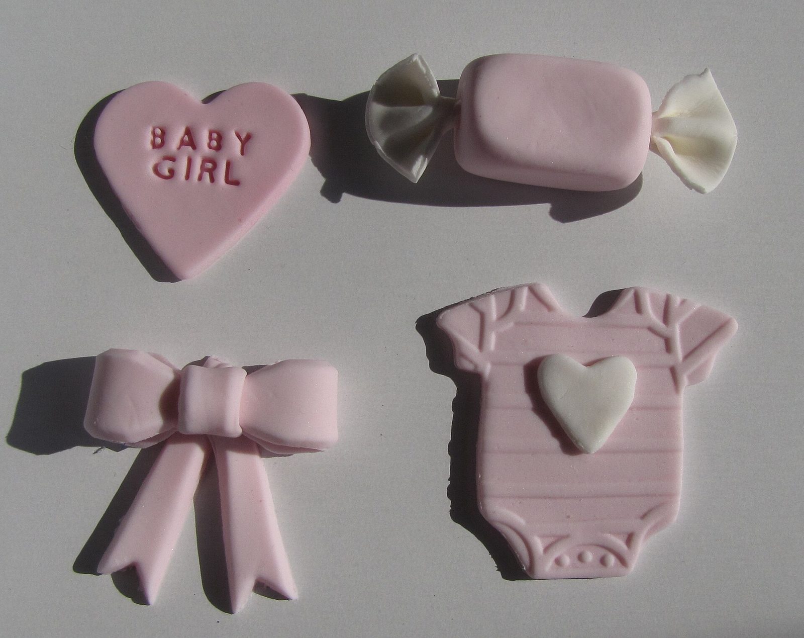 Biscoitos decorados em formato de body, laço e coração para chá de bebê