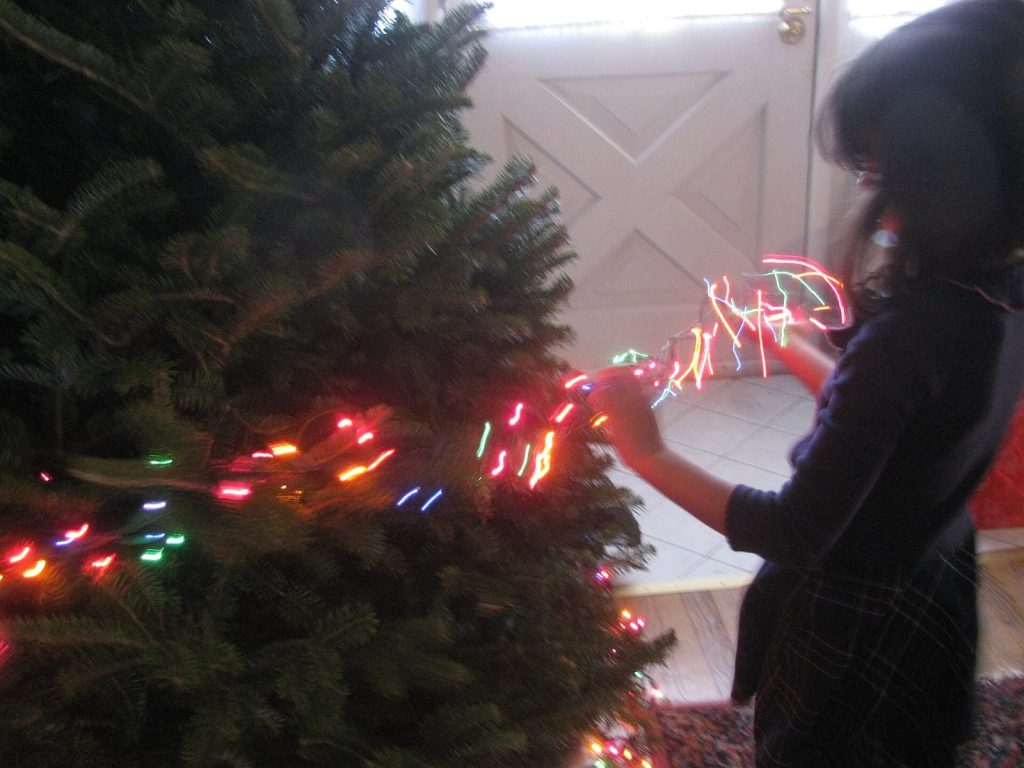 Pessoa colocando pisca-pisca colorido na árvore de Natal
