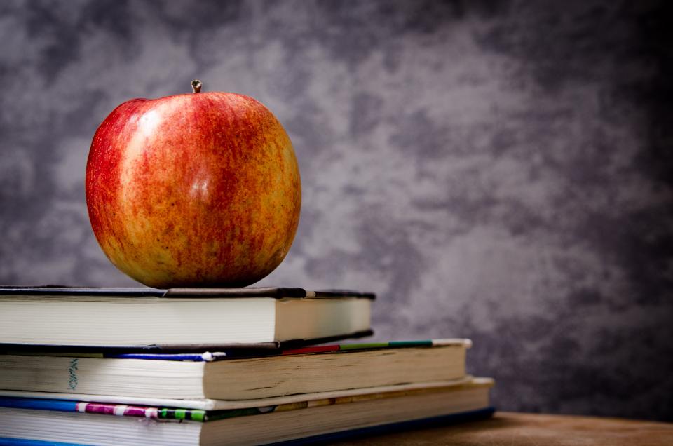 Maçã vermelha sobre uma pilha de livros, símbolo do Dia dos Professores