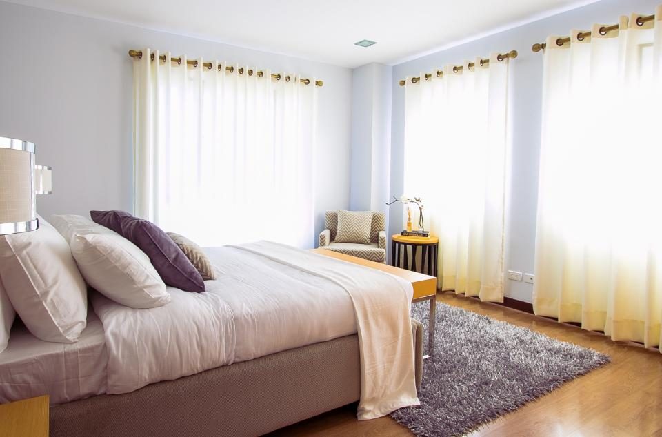 Quarto com cama de casal arrumada e manta nos pés